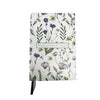 Artsy Ems Designs white eco-friendly notebook features a floral pattern with purple and yellow flowers, green leaves, a Barely grazing wild ends free label, and a black ribbon bookmark.